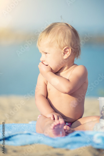 Baby playing with toys on the sandy beach near the sea. Cute little kid in sand on tropical beach. Ocean coast.