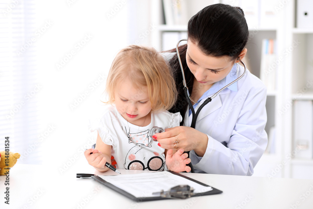 Pediatrician is taking care of baby in hospital. Little girl is being examine by doctor with stethoscope. Health care, insurance and help concept. Pediatrician is taking care of baby in hospital. Little girl is being examine by doctor with stethoscope. Health care, insurance and help concept.