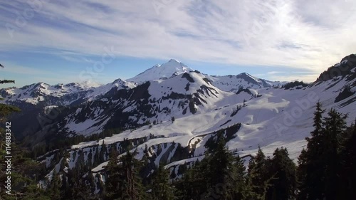 Aerial Fly Through Tree Frame to Snowy Mountain Range with Mt Baker on Sunny Day