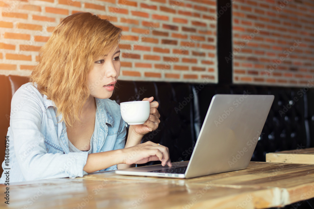 Fototapeta premium Beautiful young hipster woman using laptop at cafe.