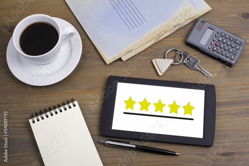 Five star rating on tablet device on a wooden table