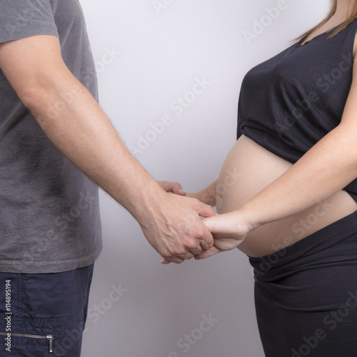 White couple holding hands with pregnant woman