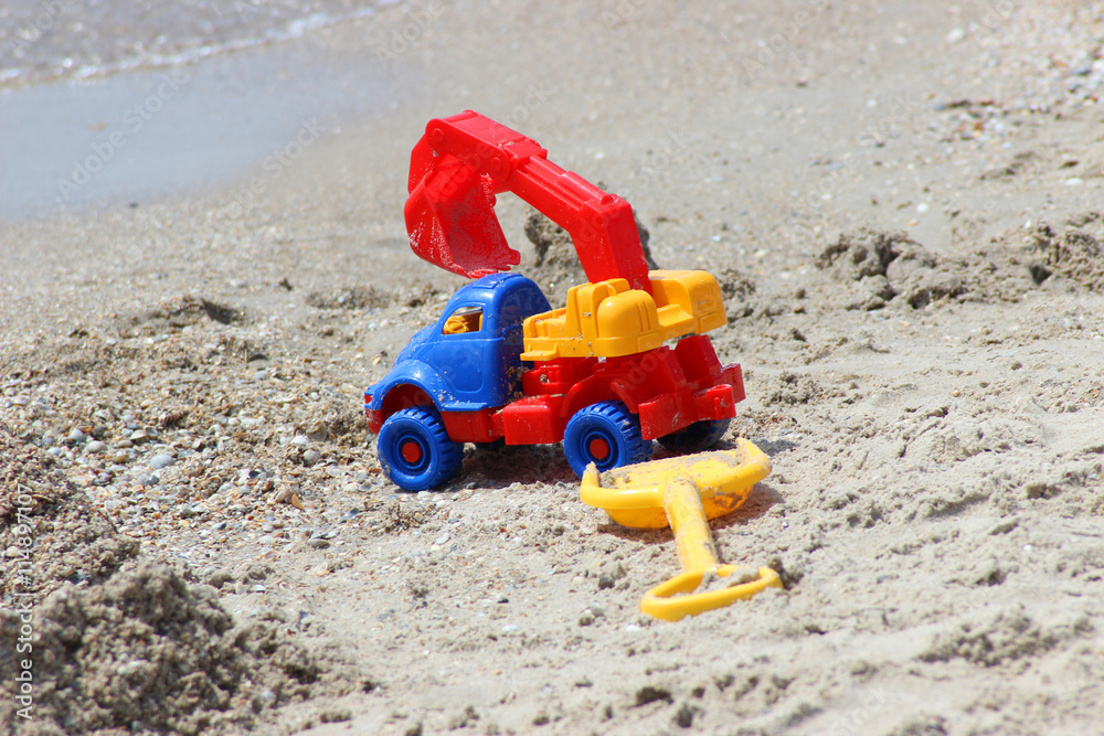 toy car-ekskovator and shovel on the sandy coast toy car-ekskovator and shovel on the sandy coast