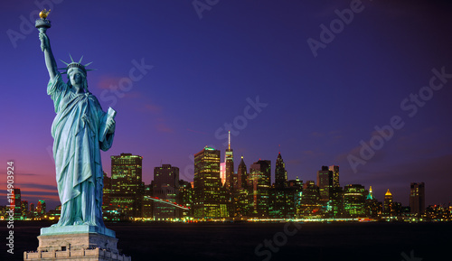 Manhattan skyline at night and Statue of Liberty.