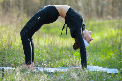 Young woman is practicing yoga at forest park
