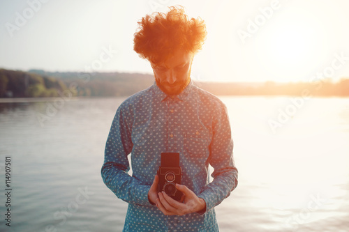 The red-haired guy holding a medium format film camera in his hands photo