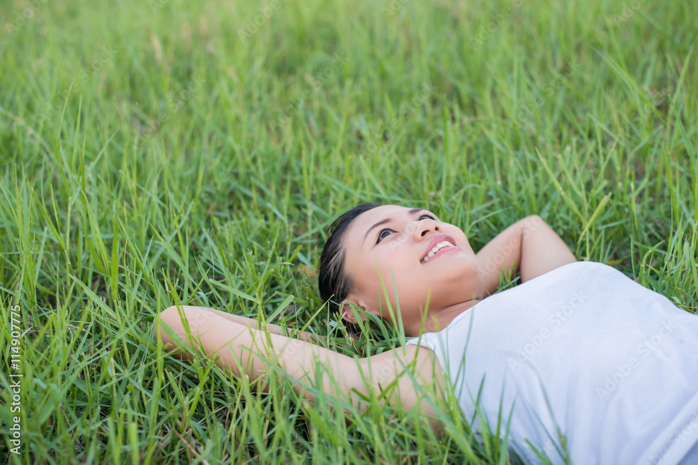 Beautiful young woman lying down in green grass meadows. Beautiful young woman lying down in green grass meadows.
