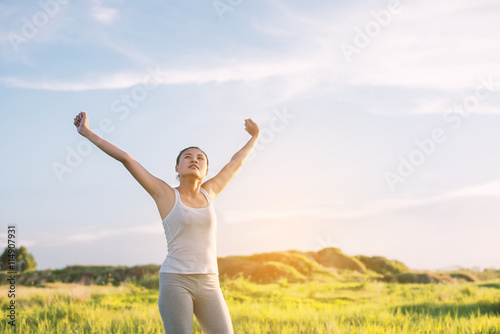 Happy beautiful woman with stretched arms in meadows with fresh