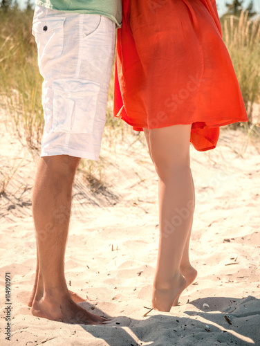 Paar steht mit Beinen und Füßen im Sand 