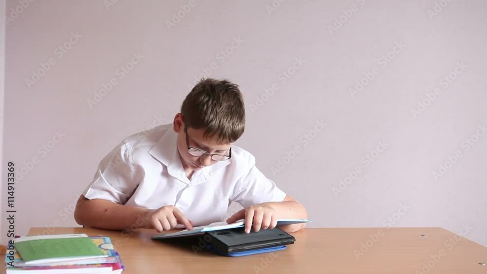 boy student reading a paragraph in the textbook sitting at a school desk boy student reading a paragraph in the textbook sitting at a school desk