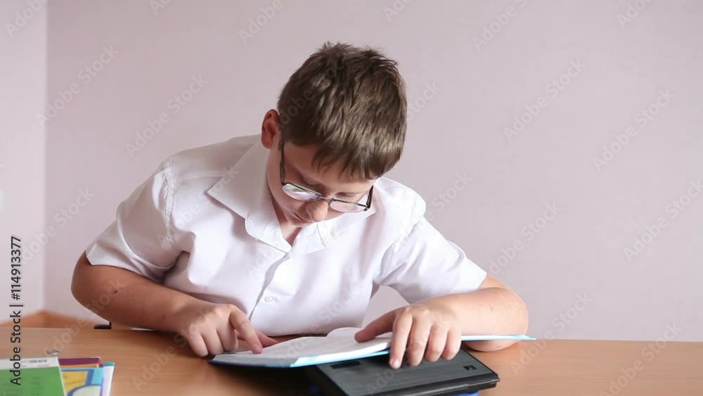 boy student reading a paragraph in the textbook sitting at a school desk boy student reading a paragraph in the textbook sitting at a school desk