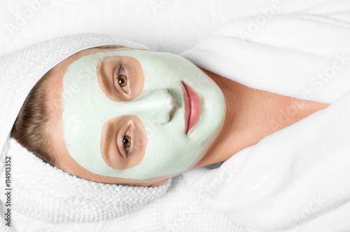Beauty Treatments. Woman applying facial mask at spa