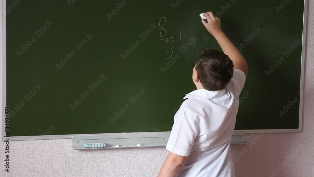 Teen student solves an example on the blackboard Teen student solves an example on the blackboard