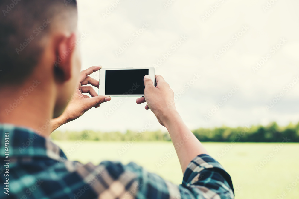Young hipster man using smartphone taking the landscape photogra
