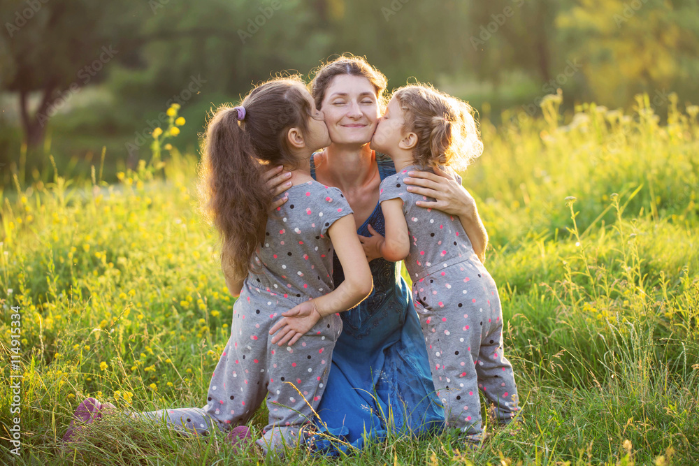 Fototapeta premium Children kissing mother outdoors.