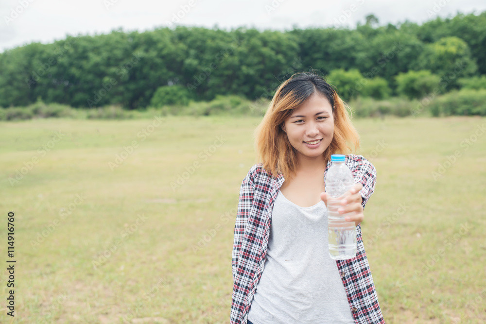 young hipster woman holding bottle of water at summer green park young hipster woman holding bottle of water at summer green park