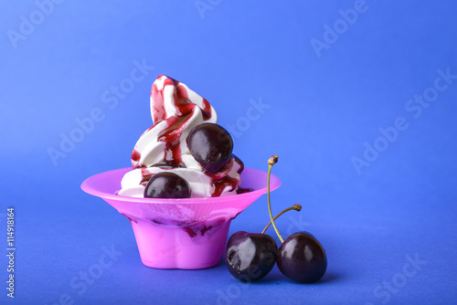 frozen yogurt with black cherry cream and cherry topping on blue background