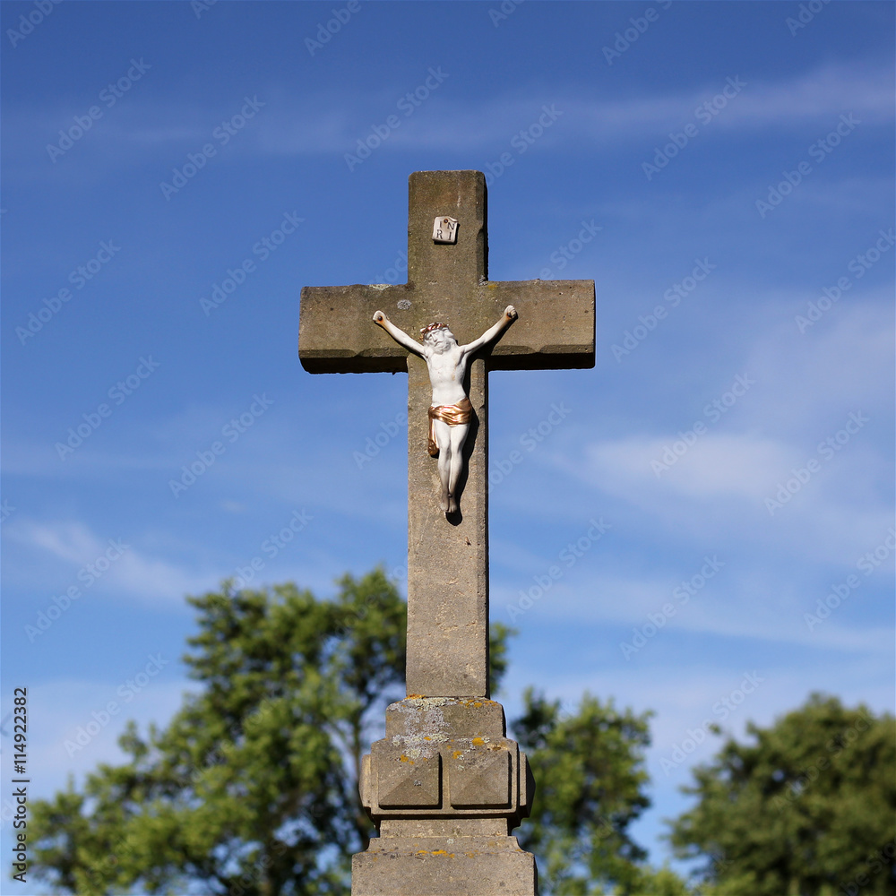 Old figure Christ on the stony cross at cemetery, stony crucifix