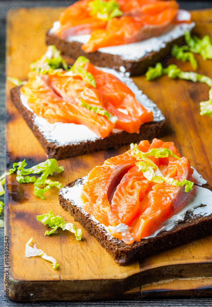 Sandwich with cereals black bread and salmon on wooden board background Sandwich with cereals black bread and salmon on wooden board background