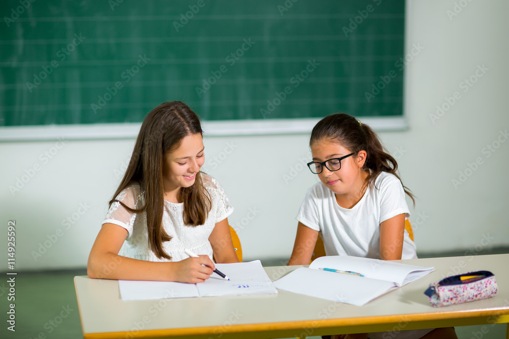 Portrait of two happy schoolgirls in a classroom.