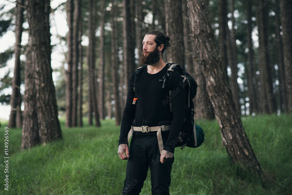 Bearded man with backpack trekking in forest