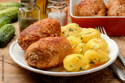 Roasted meat roulades sereved  with baked potatoes. On wooden background. photo