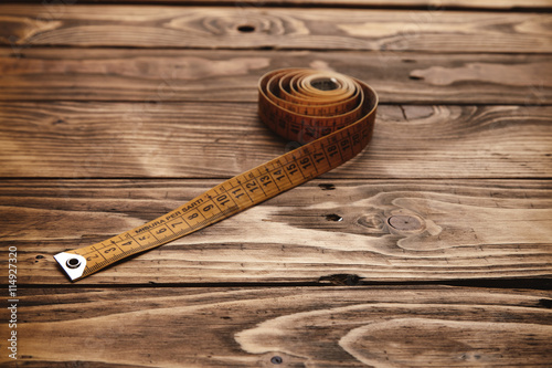 Vintage tailor ruler rolled isolated on rustic wooden table close up photo