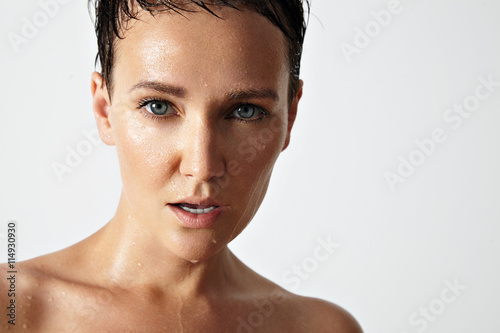 wet woman with a drops of water on her skin watching at camera