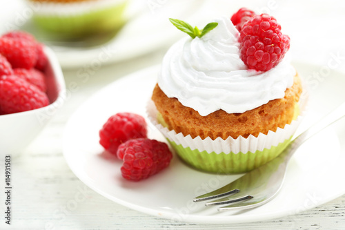 Raspberry cupcakes on plate on white wooden background