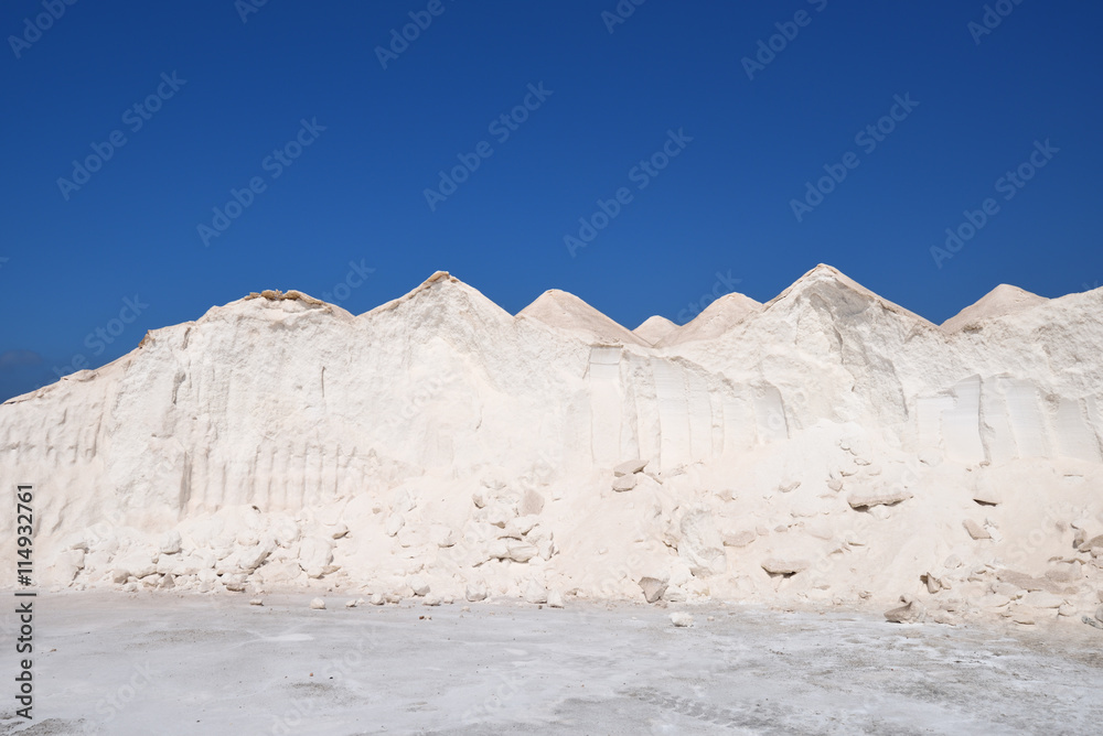 Big piles of white sea salt under a blue sky