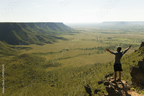 Man with open arms against the wind admires the mountains landscape on the sunrise