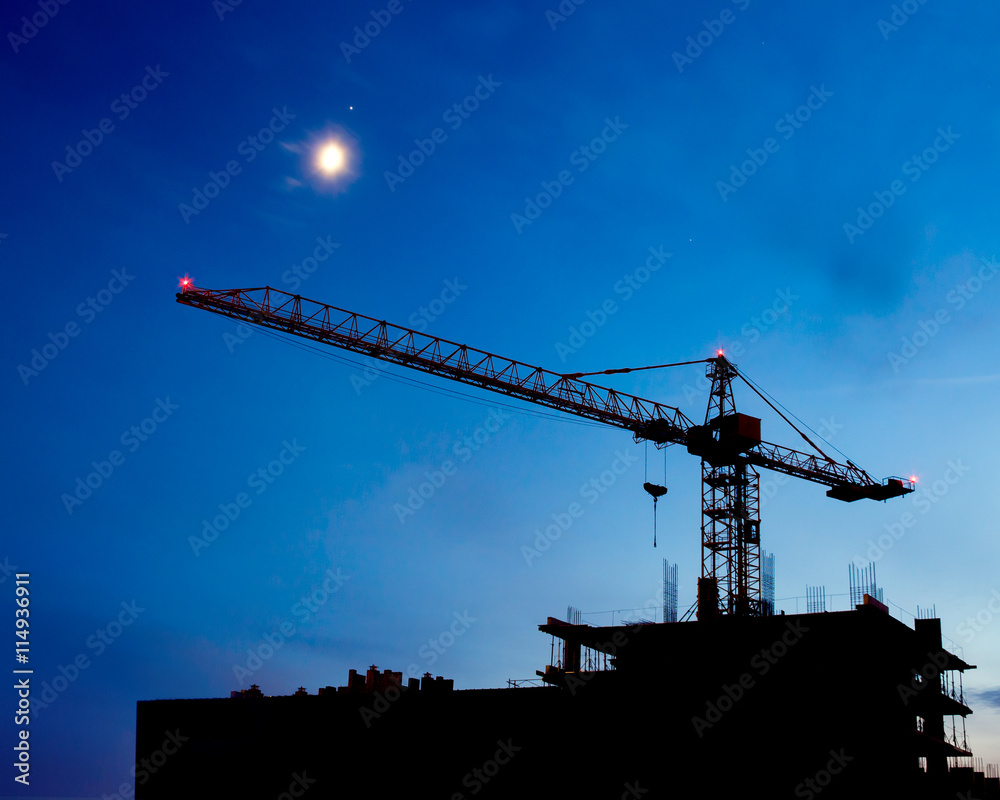 Construction Site. Industrial construction cranes and building silhouettes on night sky. Beautiful colorful night landscape.