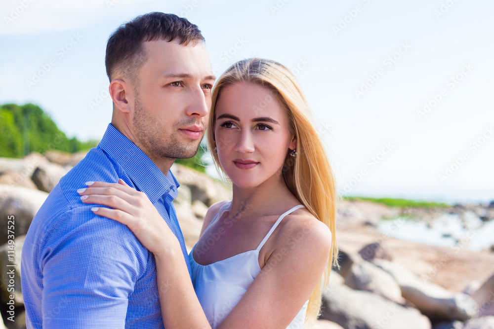 happy young beautiful couple on rocky beach