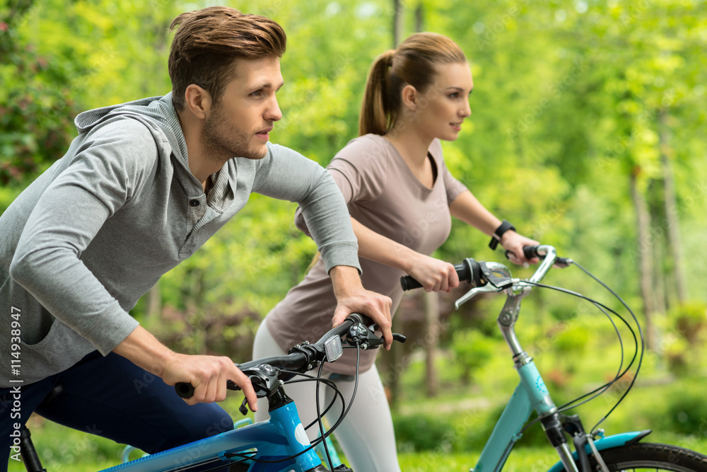 Cute man and woman riding bikes in park