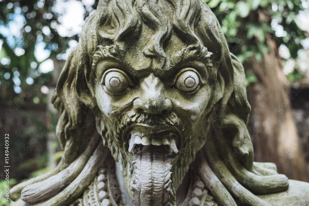 Close up view of carved traditional demon guard statue in stone in Indonesia, Bali.