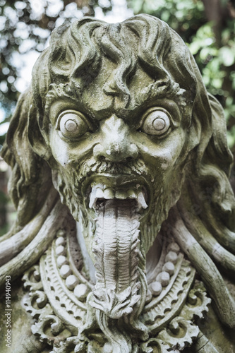 Close up view of carved traditional demon guard statue in stone in Indonesia, Bali.