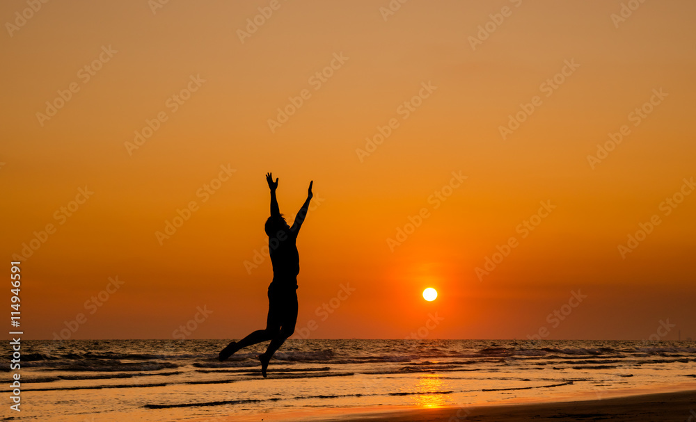 silhouette of a happy man jumping on a sunset