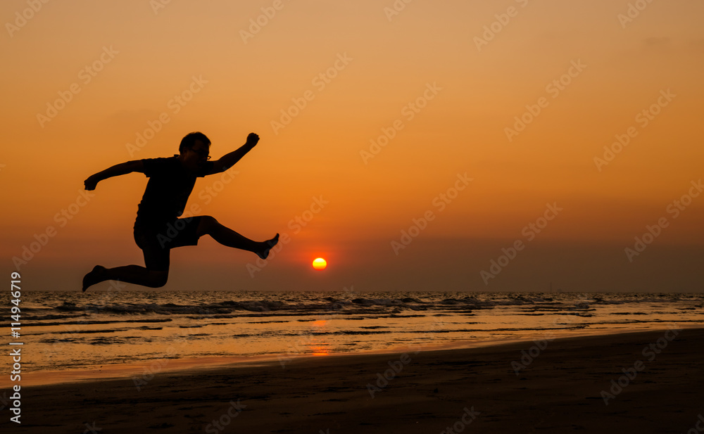 silhouette of a happy man jumping on a sunset