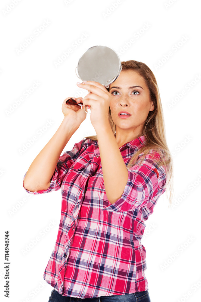 Young woman holding a mirror and combing her hair Young woman holding a mirror and combing her hair