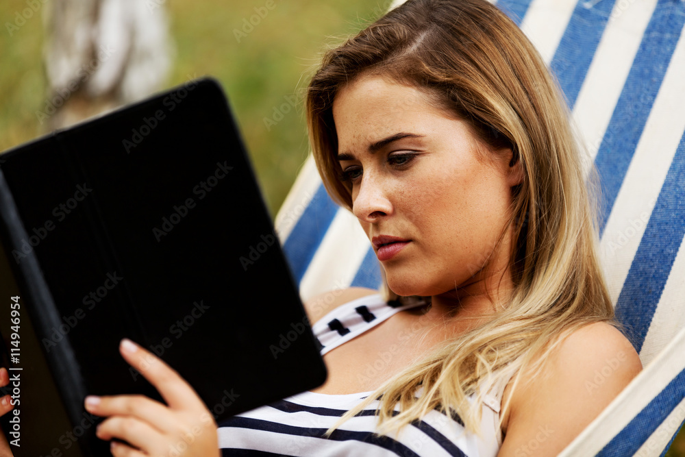 Fototapeta premium Young woman with tablet on the hammock