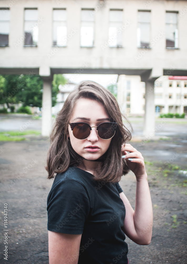 A young girl with beautiful hair and dress a black shirt waiting for friends. She straightens hair at school. The girl walk in a city. Pretty Girl. Wind develops hair A young girl with beautiful hair and dress a black shirt waiting for friends. She straightens hair at school. The girl walk in a city. Pretty Girl. Wind develops hair