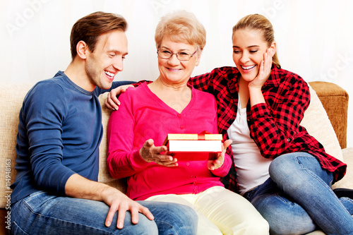 Happy family - couple with old woman who holding gift box photo