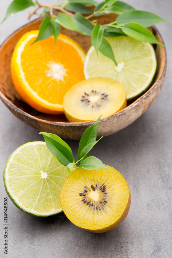 Mixed citrus fruit lemons, orange, kiwi, limes on a gray backgro Mixed citrus fruit lemons, orange, kiwi, limes on a gray backgro