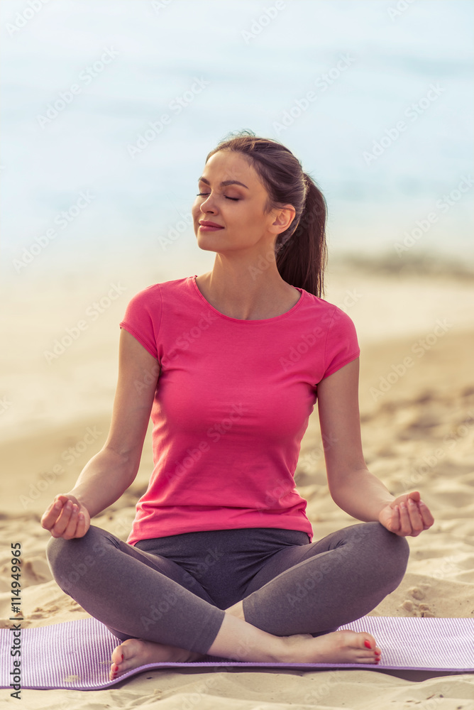 Girl doing yoga on the beach