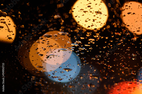 Abstract raindrops on glass and lights on the road, soft focus.