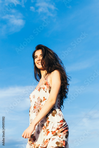 Woman with a dress smiling with a blue sky in the background