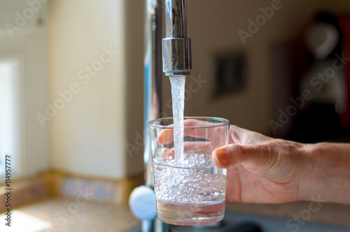 Woman filling a glass of water from a tap
