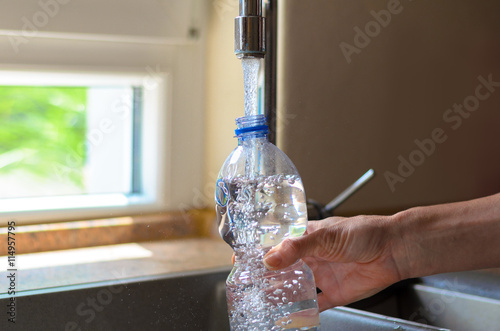 Fotografie Woman filling a plastic bottle with water