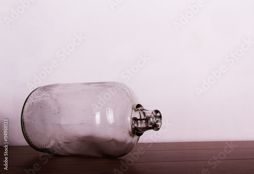 Clear glass demijohn against a light background