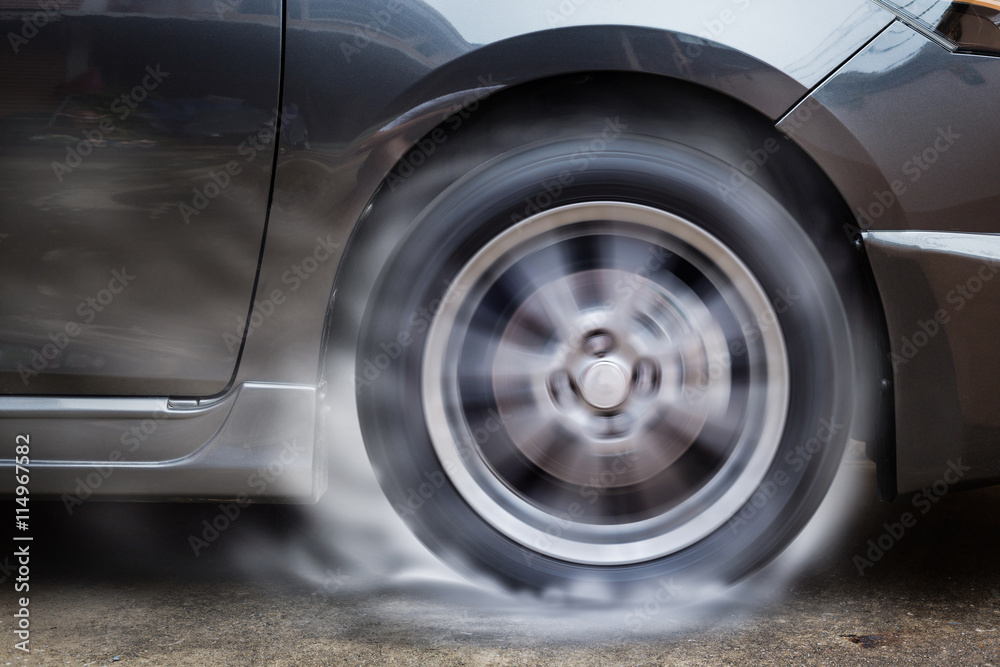 Car racing spinning wheel burns rubber on floor.